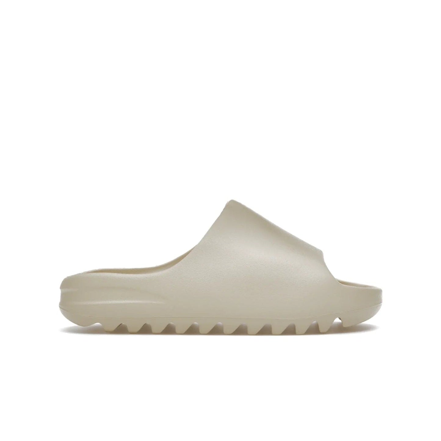 adidas Yeezy Slide Bone (2022 Restock) - Image 1 - Only at www.BallersClubKickz.com - Stay comfy with the adidas Yeezy Slide Bone - a fashionable silhouette with all-day comfort. This Bone/Bone/Bone colorway combines style and comfort with a pebbled texture and grooved sole. Restocked in May 2022, this shoe is the perfect addition to your collection.