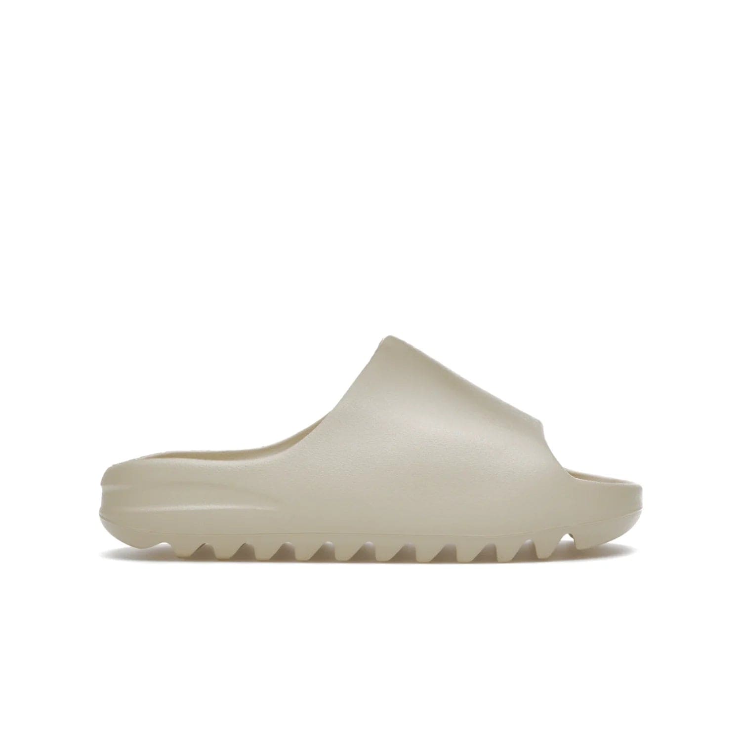 adidas Yeezy Slide Bone (2022 Restock) - Image 1 - Only at www.BallersClubKickz.com - Stay comfy with the adidas Yeezy Slide Bone - a fashionable silhouette with all-day comfort. This Bone/Bone/Bone colorway combines style and comfort with a pebbled texture and grooved sole. Restocked in May 2022, this shoe is the perfect addition to your collection.